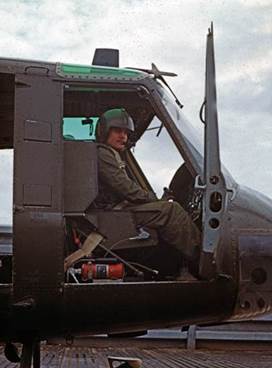 A person in a military uniform sitting in the cockpit of a helicopter

Description automatically generated