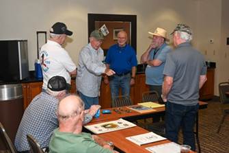 A group of men standing around a table

Description automatically generated