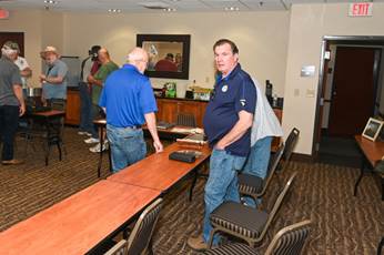 A group of men standing around a table

Description automatically generated