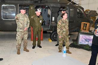 A group of military personnel standing in front of a helicopter

Description automatically generated